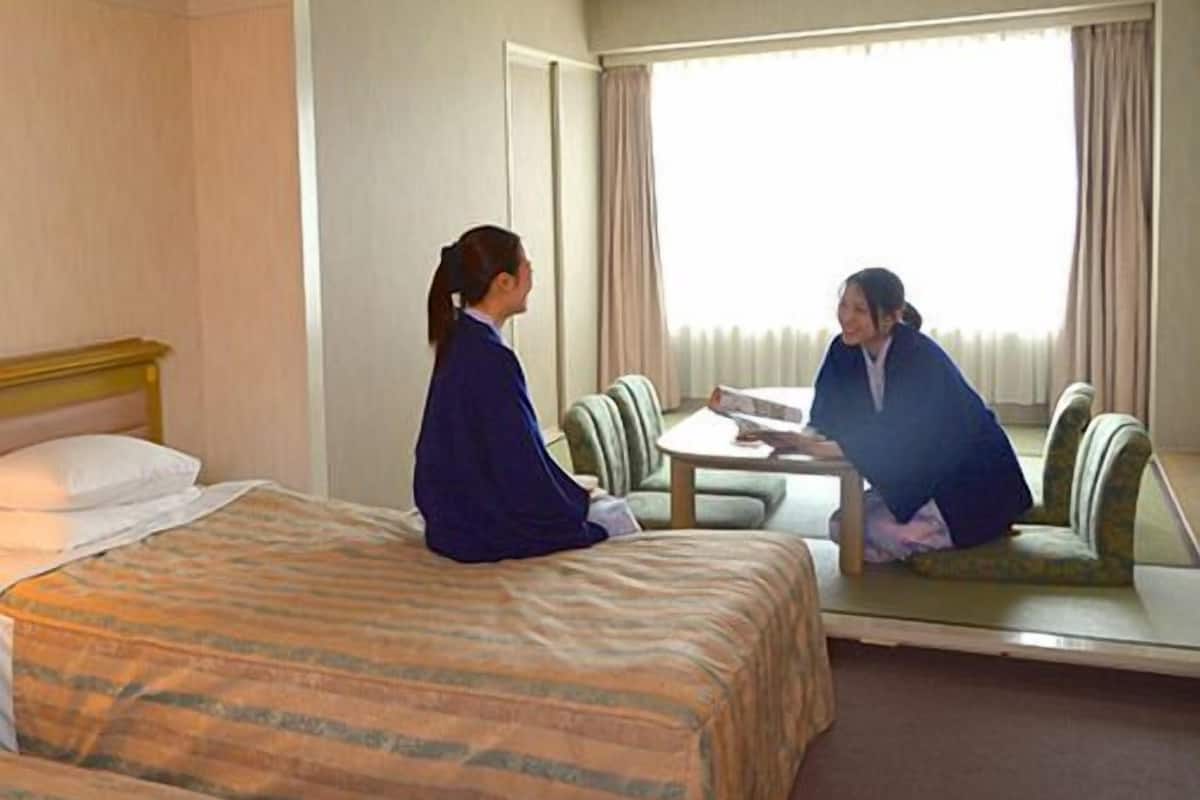 A hotel room with a bed, a table, and a mirror.