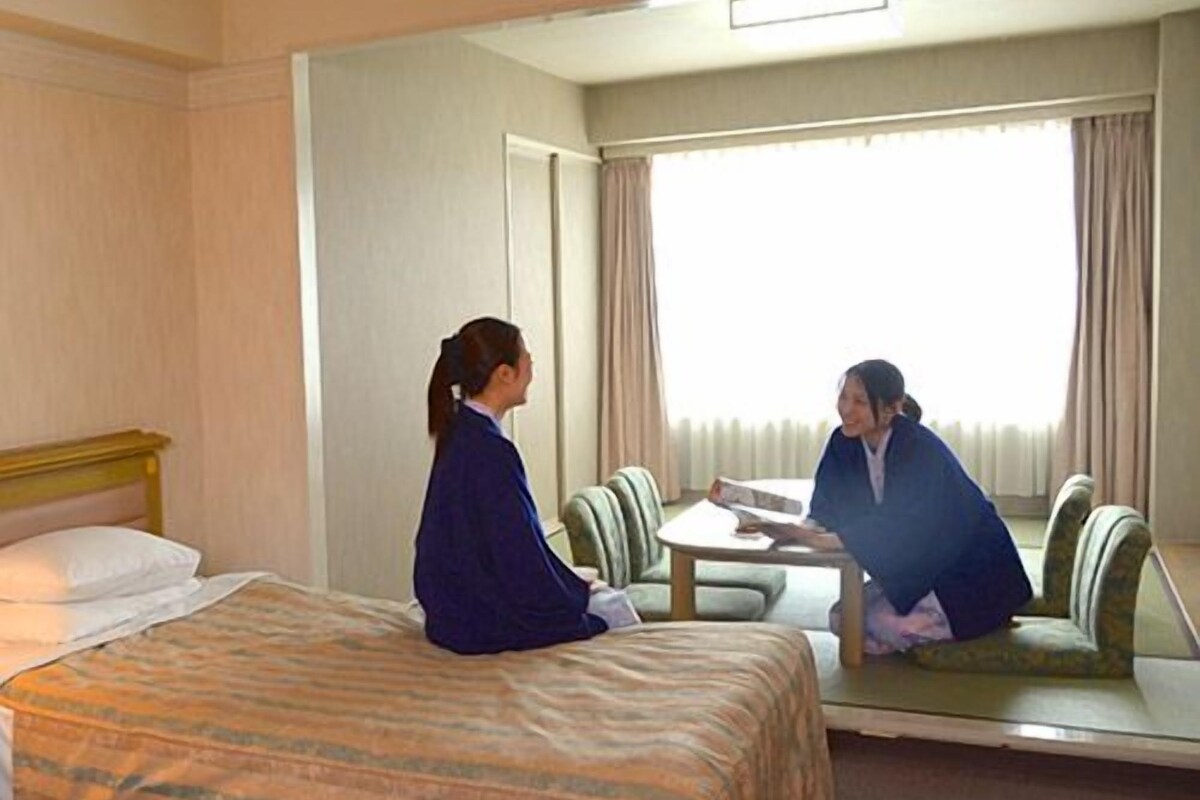 A hotel room with a bed, a table, and a chair.