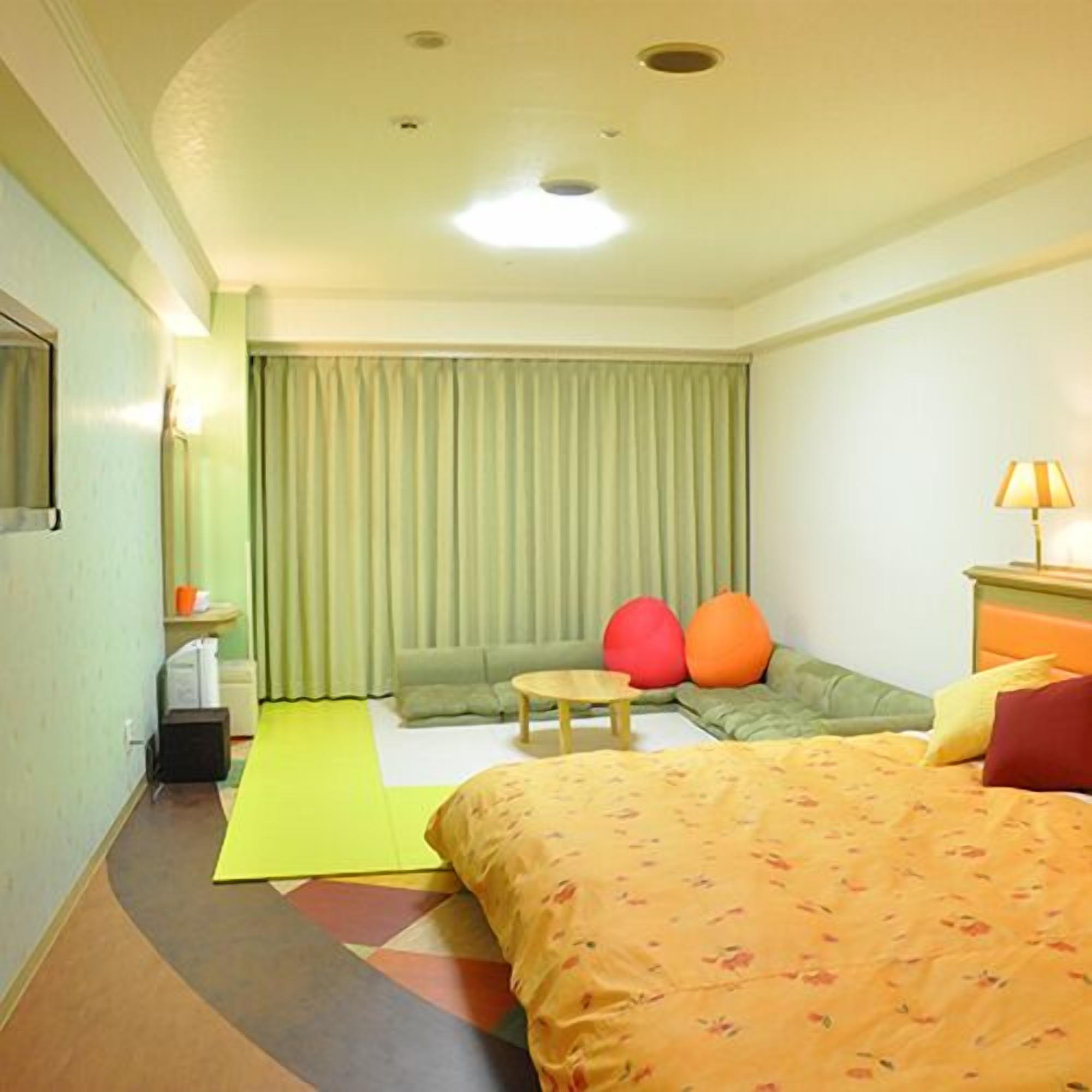 A hotel room with a bed, a sofa, a small table, and a lamp.