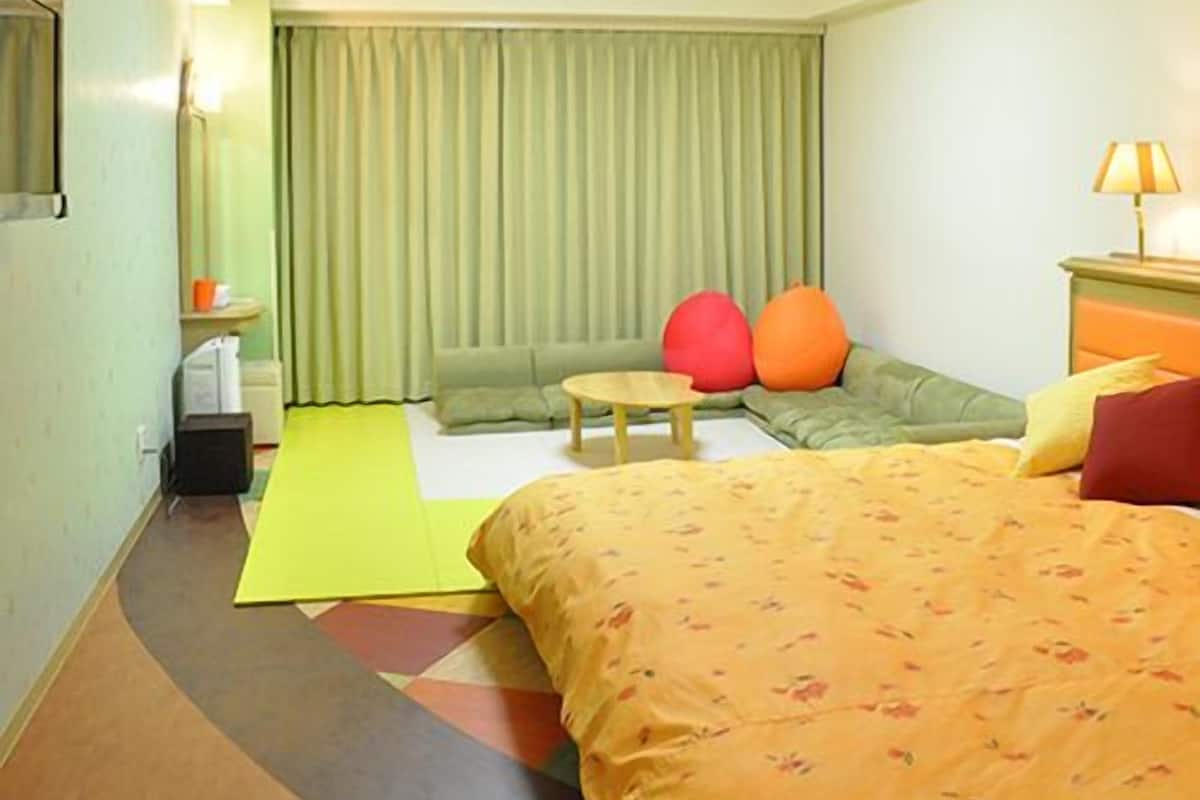 Ein Hotelzimmer mit Bett, Sofa, einem kleinen Tisch und einer Lampe.