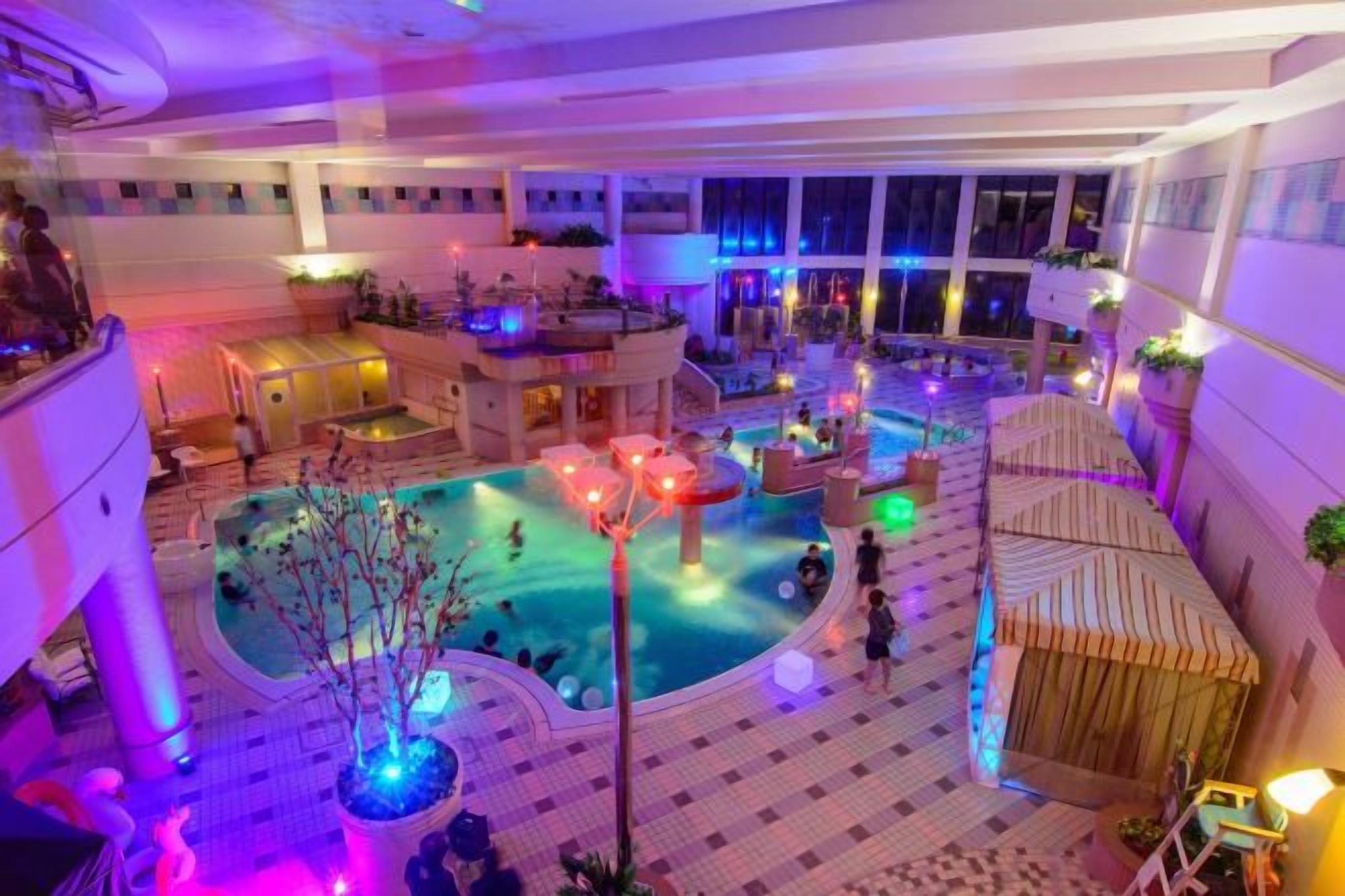 An indoor pool area with multiple levels, seating areas, and a central water feature.