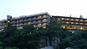 Ein mehrstöckiges Hotel mit Balkonen, umgeben von üppiger Vegetation und einem Fluss mit Felsen.