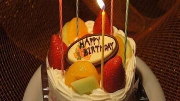A birthday cake with candles and fruit on top.