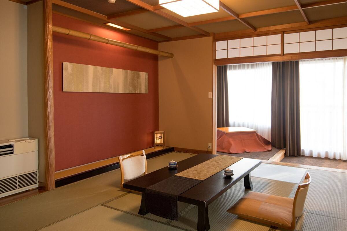 Une pièce de style japonais traditionnel, avec un sol recouvert de tatamis, une table basse et une porte coulissante donnant sur un balcon.