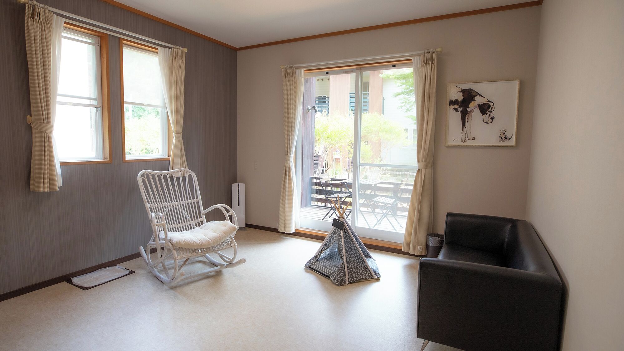 A room with a white rocking chair, a black armchair, a small table, and a sliding glass door leading to an outdoor area.
