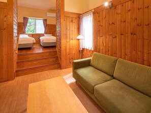 L’intérieur d’un chalet en bois, avec un canapé, deux lits et un escalier.
