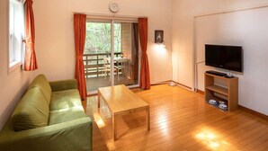 A living room with a sofa, a coffee table, a TV stand, and a sliding glass door leading to an outdoor area. - Hotel Forest Hills Nasu With Dogs (Nasu)