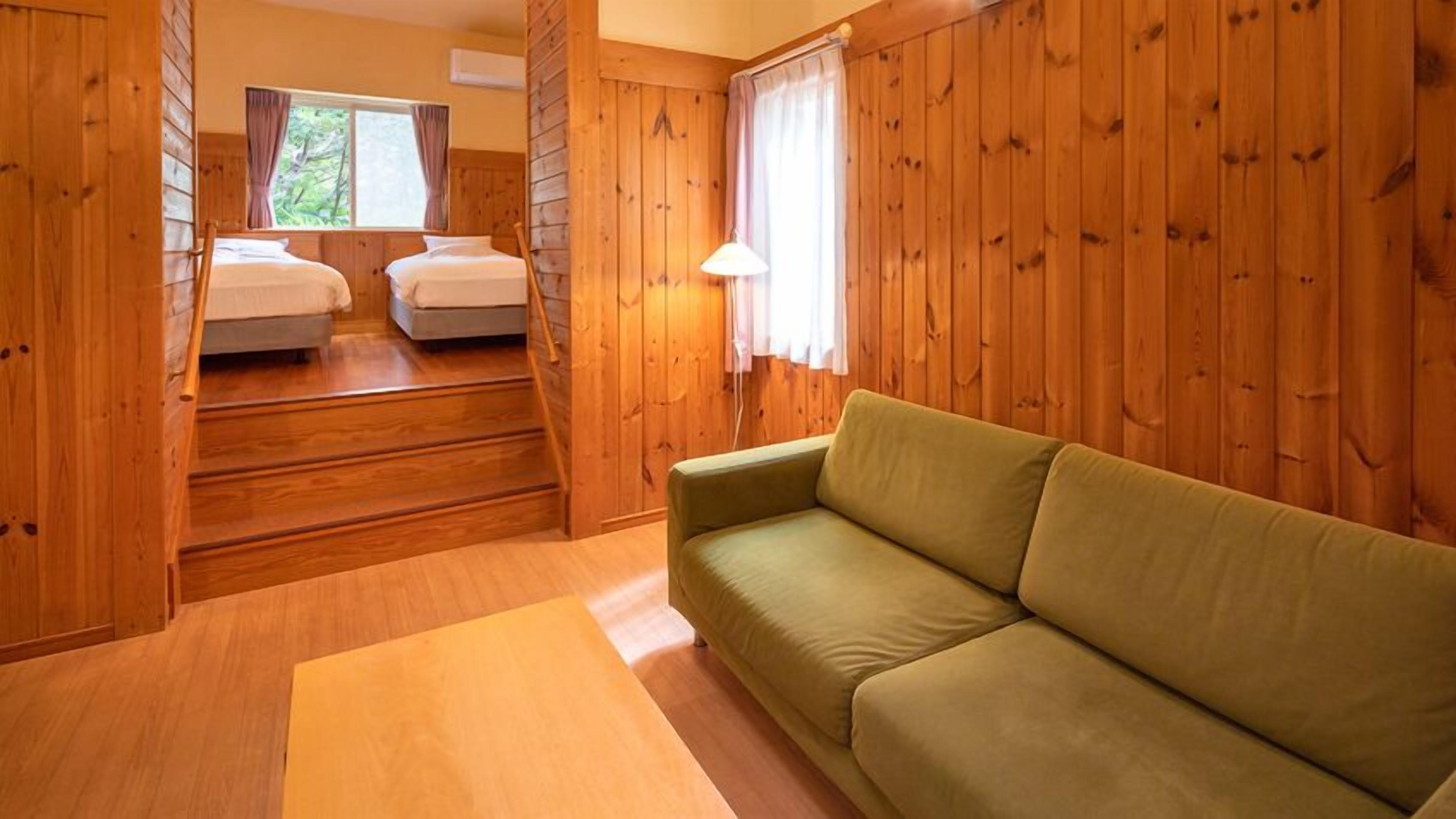 A wooden interior with a sofa and two beds.