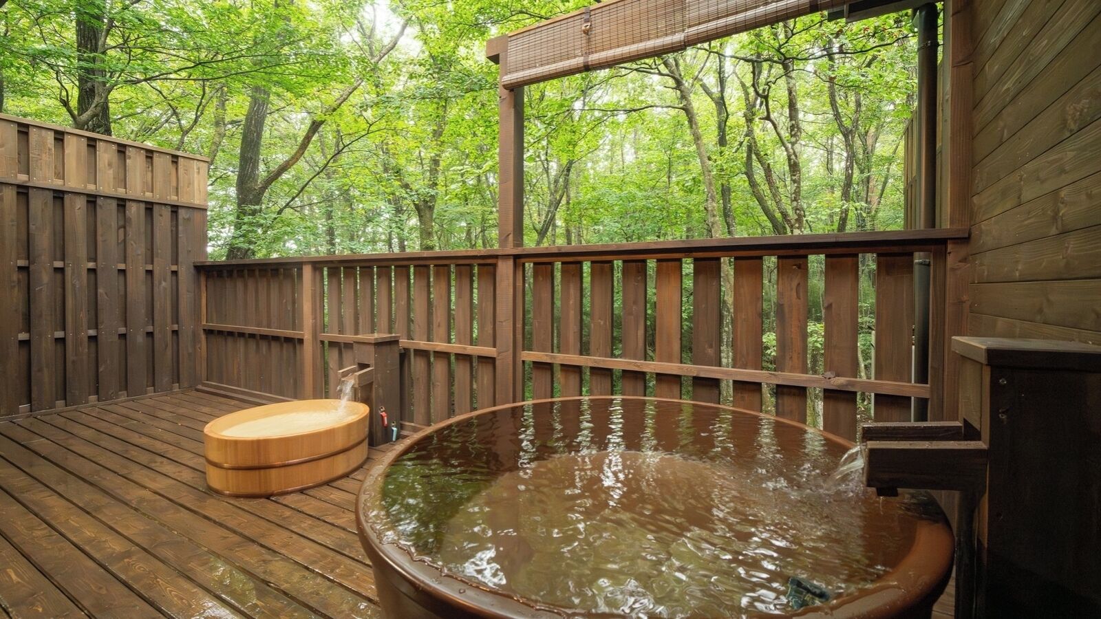 A wooden deck with a hot tub and a wooden bench, surrounded by trees.
