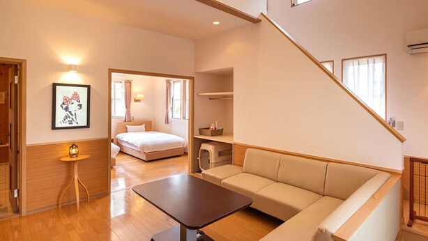 A modern living room with a sofa, a coffee table, and a bed in the background. - Hotel Forest Hills Nasu With Dogs (Nasu)