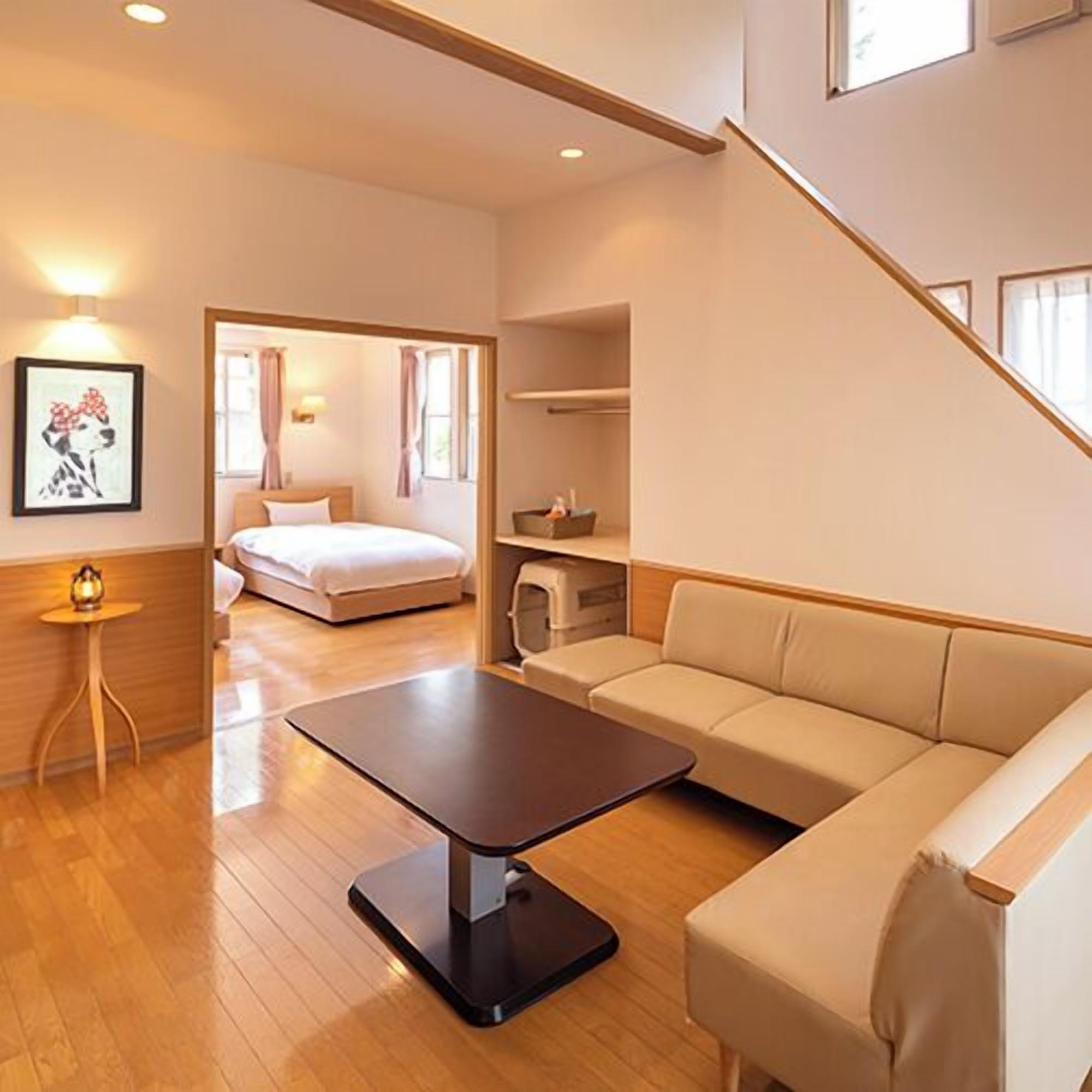 A hotel room with a bed, a sofa, a small table, and a staircase.