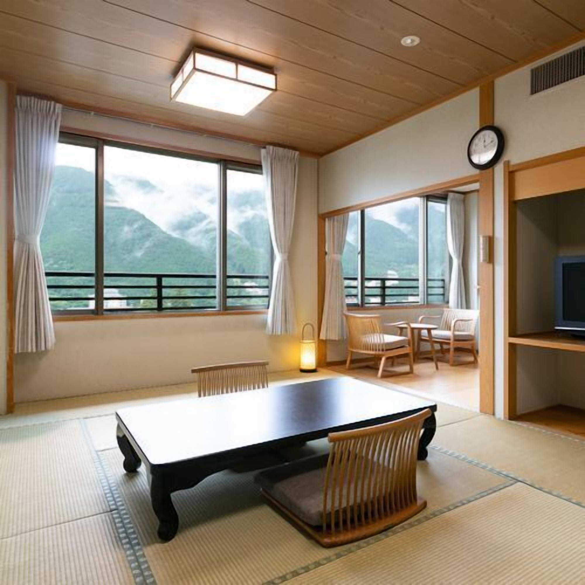 A room with a large window, a table, chairs, a TV, and a clock.