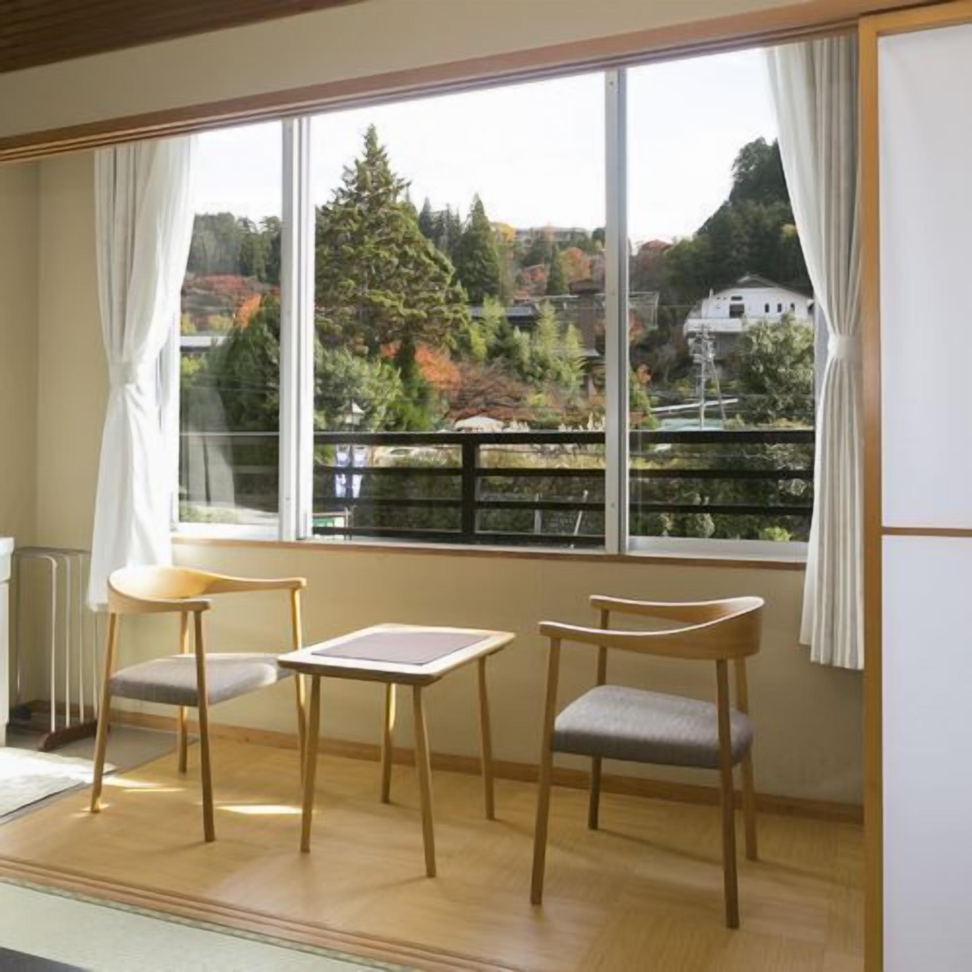 A room with a large window, two chairs, a small table, and a radiator.