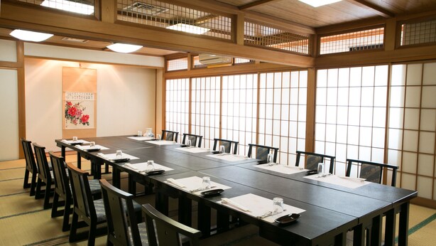 A conference room with a long table, chairs, and a traditional Japanese shoji screen. - Hotel Sunroute Tochigi (Tochigi)