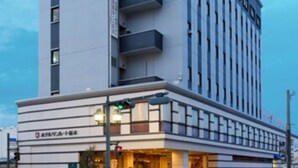 A modern hotel with a prominent red and white sign on the top, multiple balconies, and a ground-level entrance with a visible entrance door. - Hotel Sunroute Tochigi (Tochigi)