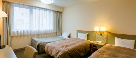 A hotel room with two beds, a desk, and a lamp.