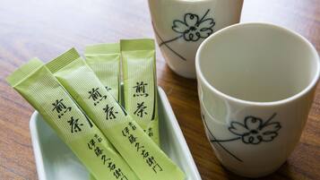 A tray with four green packets and two white cups with floral designs.