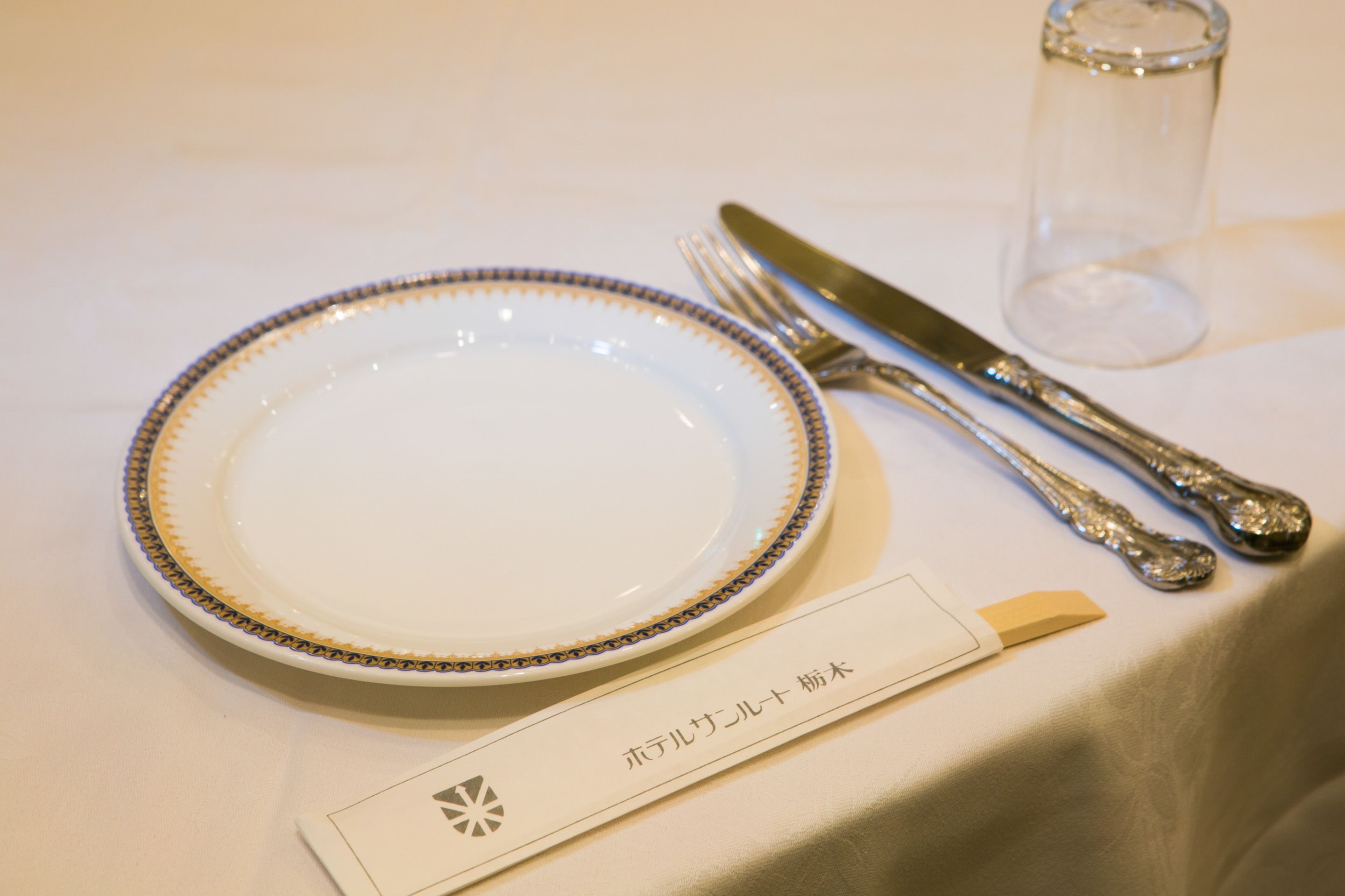 A table set with a plate, fork, knife, and a small glass.