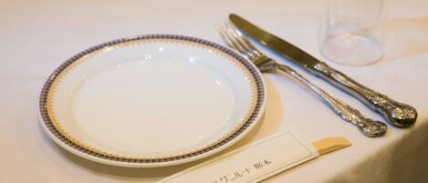 A table set with a plate, fork, knife, and a small glass.