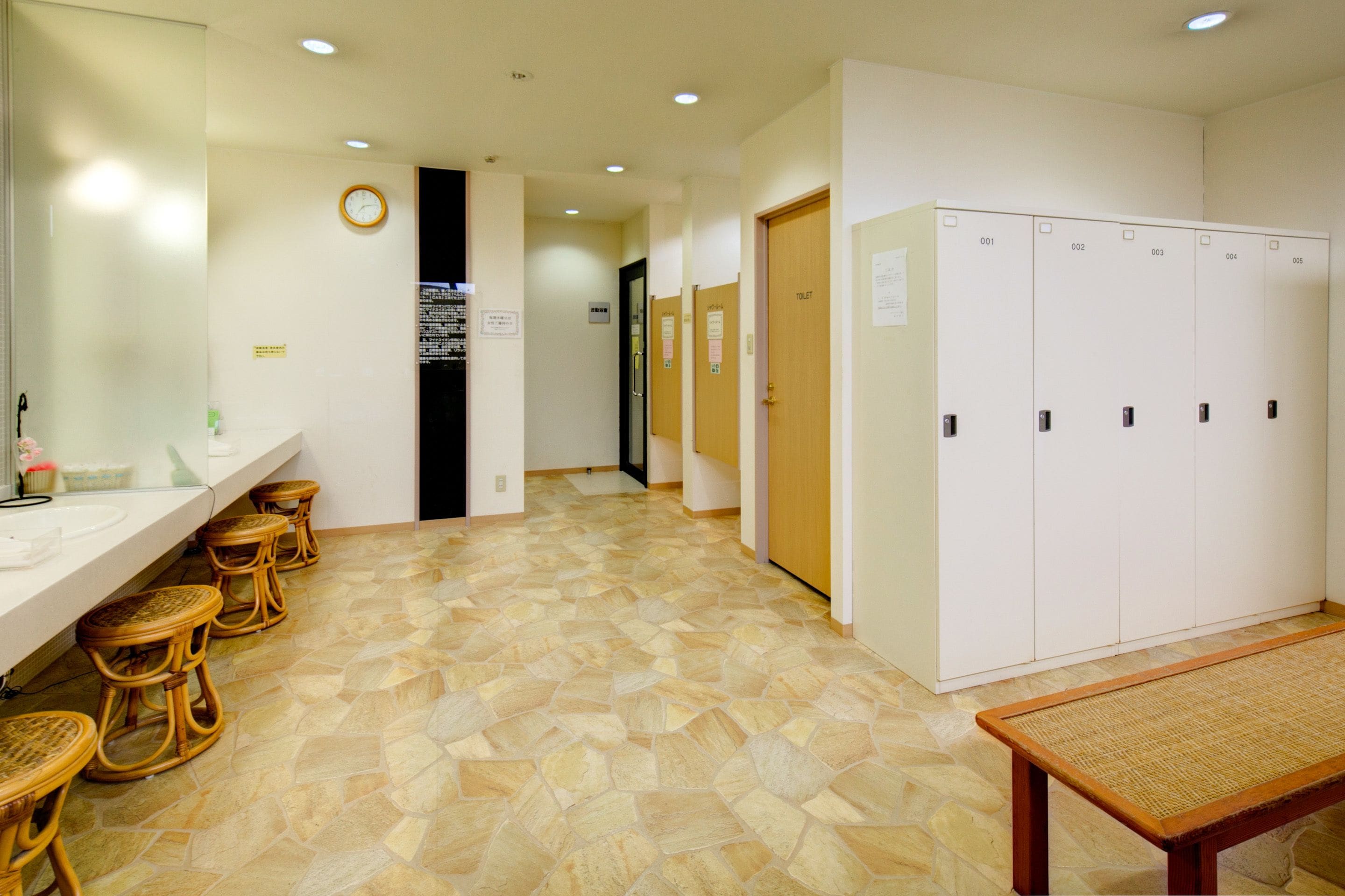 A hotel lobby with a reception area, a restroom, and a row of lockers.