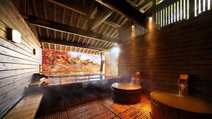 A sauna with wooden walls and benches, a steam room, and a view of autumn foliage through a window. - Kishigon Ryokan (Shibukawa)