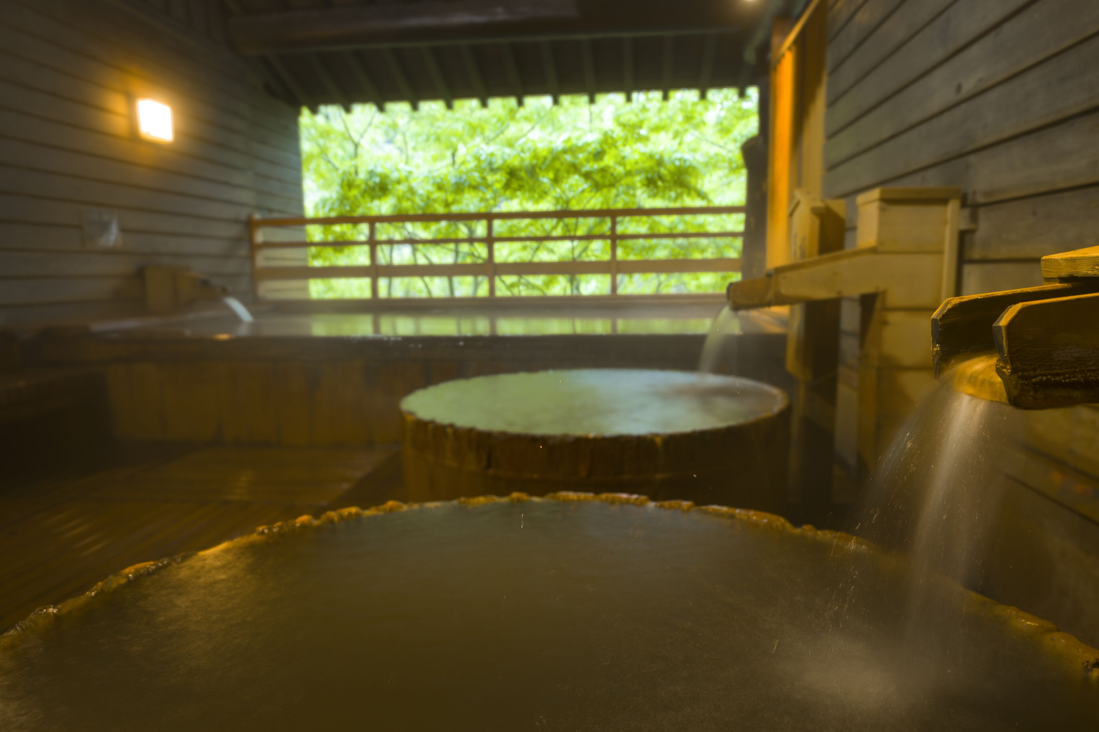A hot spring bath area with wooden benches and a wooden railing.
