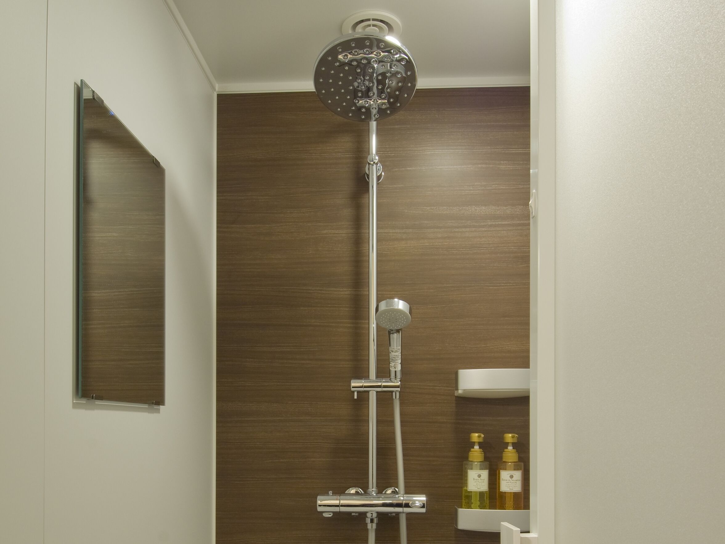 A shower with a rain showerhead, a handheld showerhead, and a handheld massage nozzle.