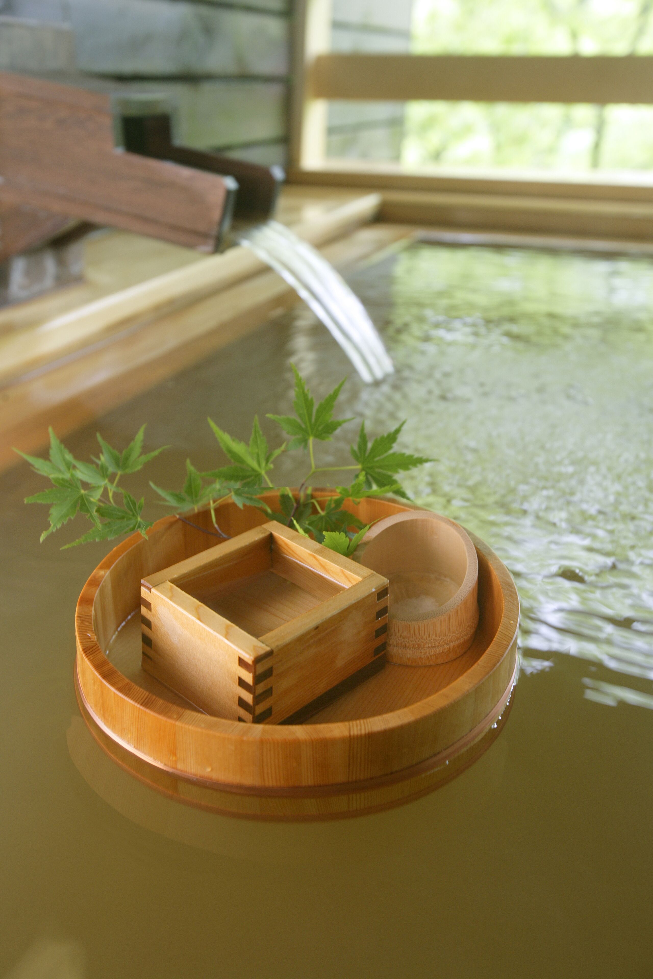 A wooden tray with a bowl and a small wooden box on a reflective surface.