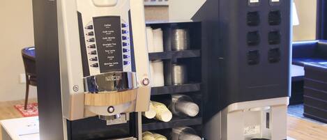 Una cafetera con varias opciones de bebidas y un dispensador de granos de café.