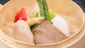 A bamboo steamer with various vegetables and meat.