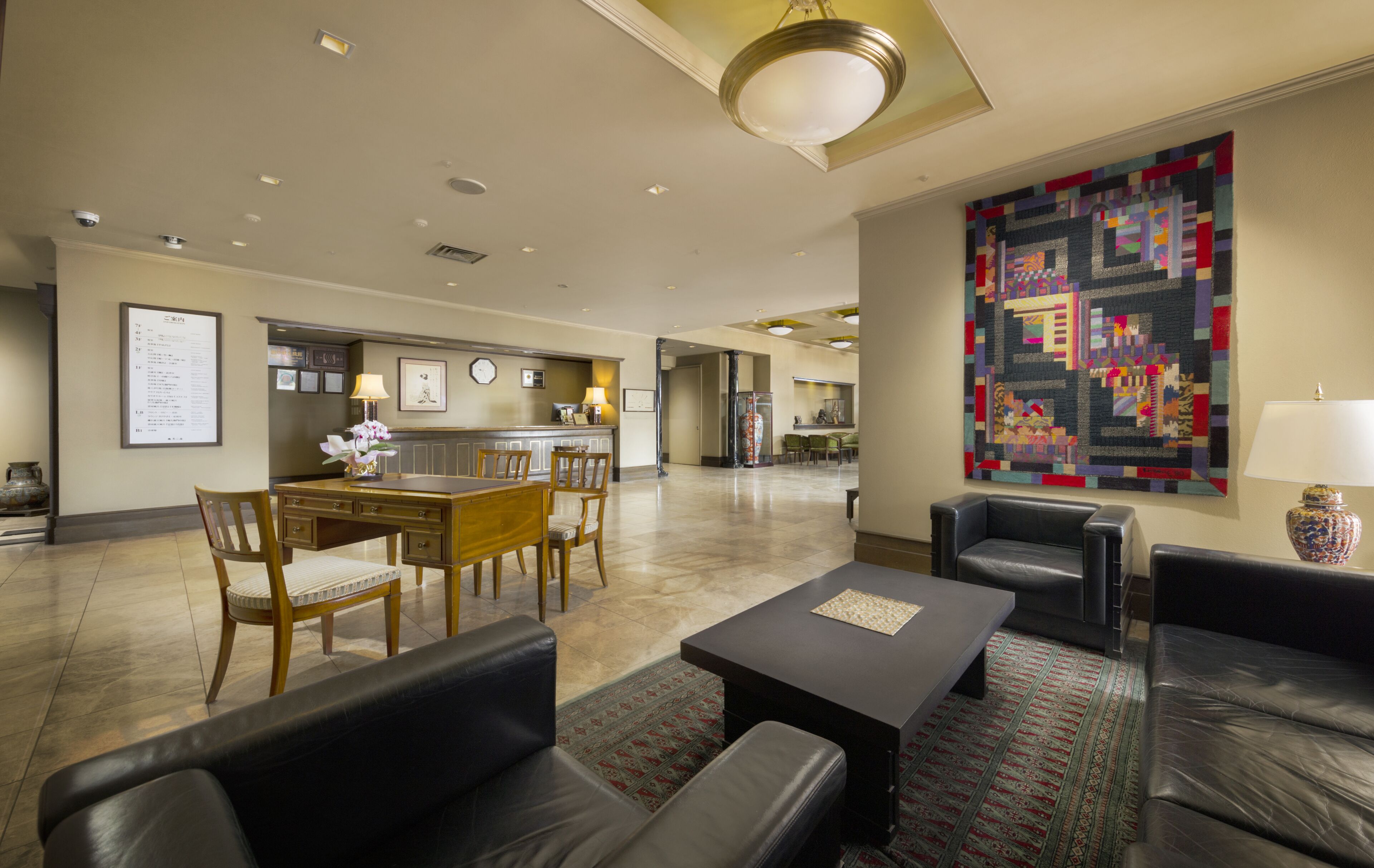 Een hotel lobby met een eetgedeelte, leren banken, een kamerbreed tapijt en een groot quilt aan de muur.