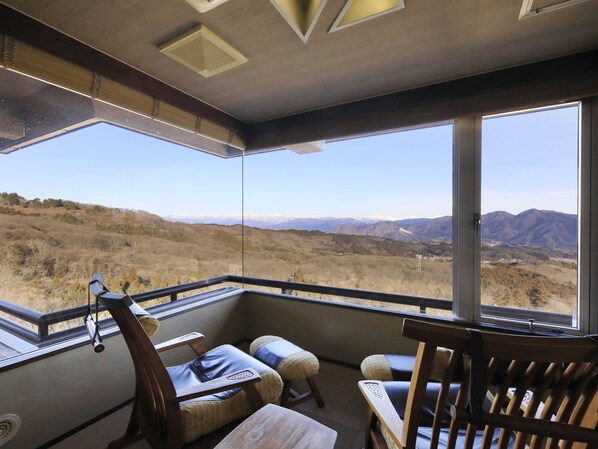 Una habitación con un ventanal que ofrece vistas a la montaña. Hay sillas de madera y una pequeña mesa.