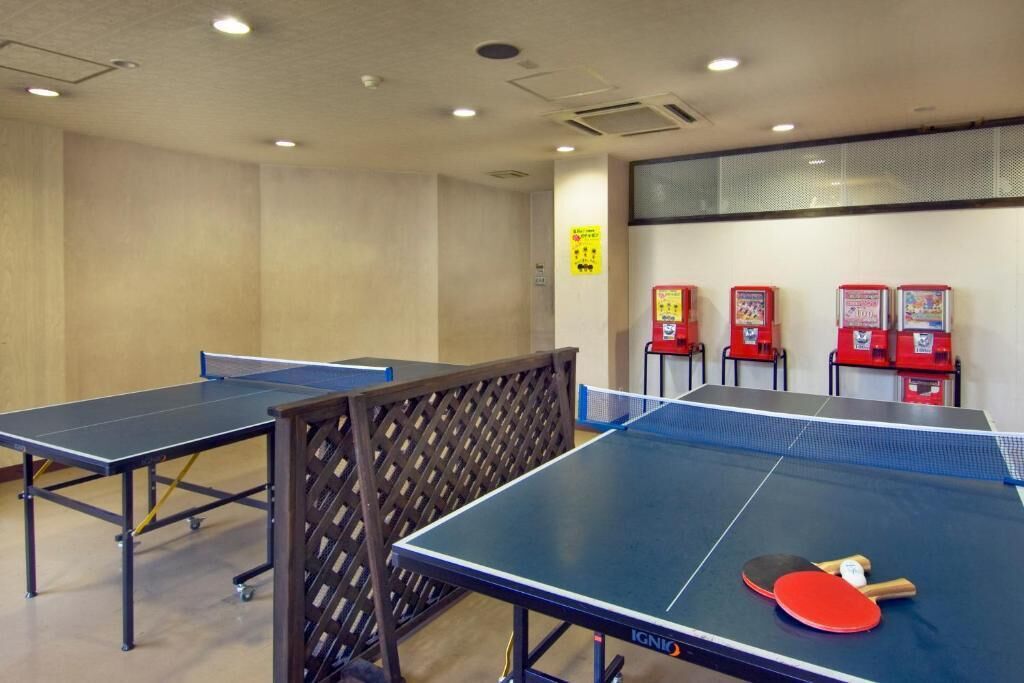 Una habitación con mesas de ping pong y máquinas expendedoras rojas.