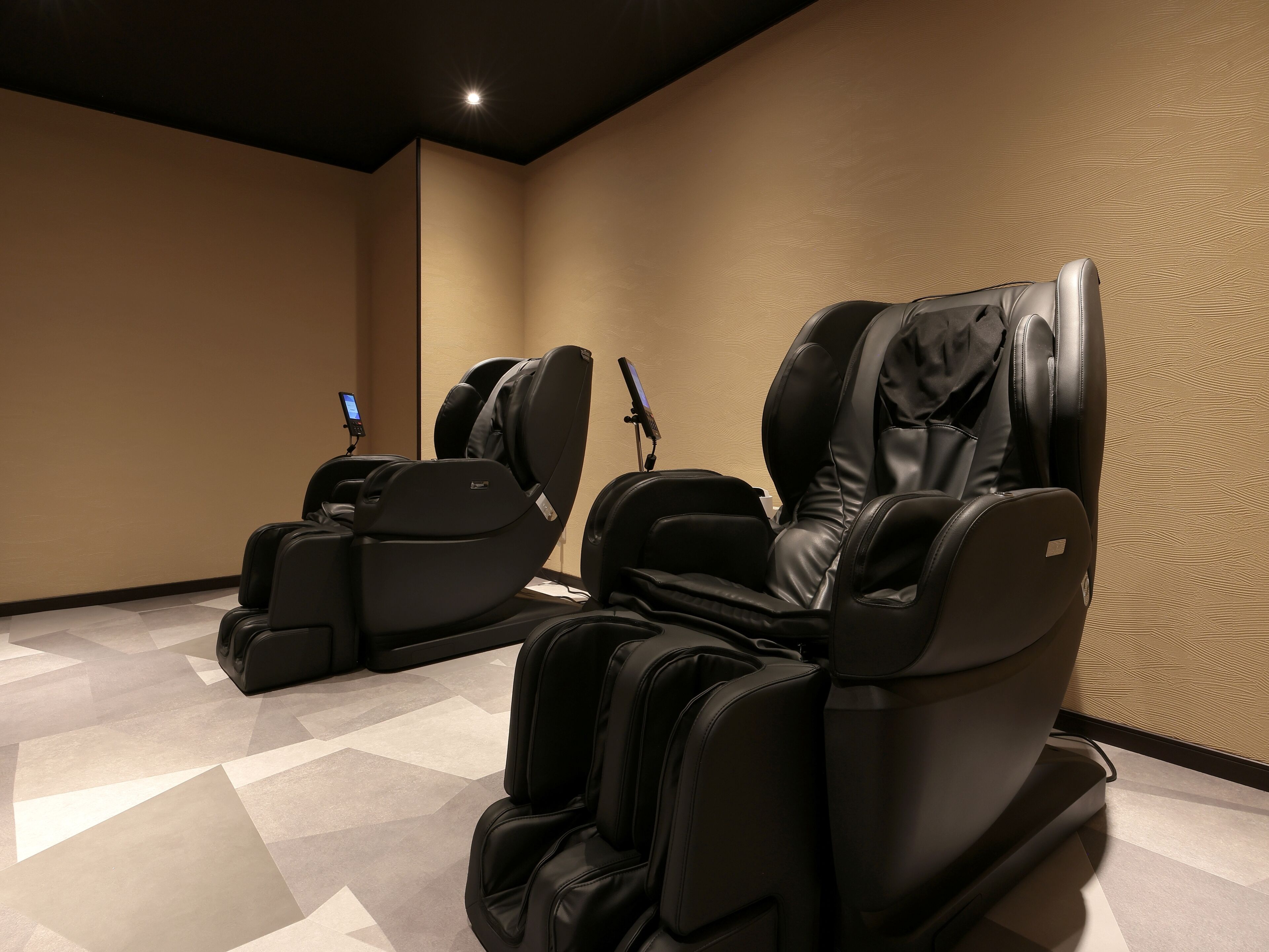 A massage room with two massage chairs and a control panel.