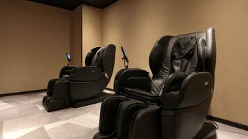 A massage room with two massage chairs and a control panel.