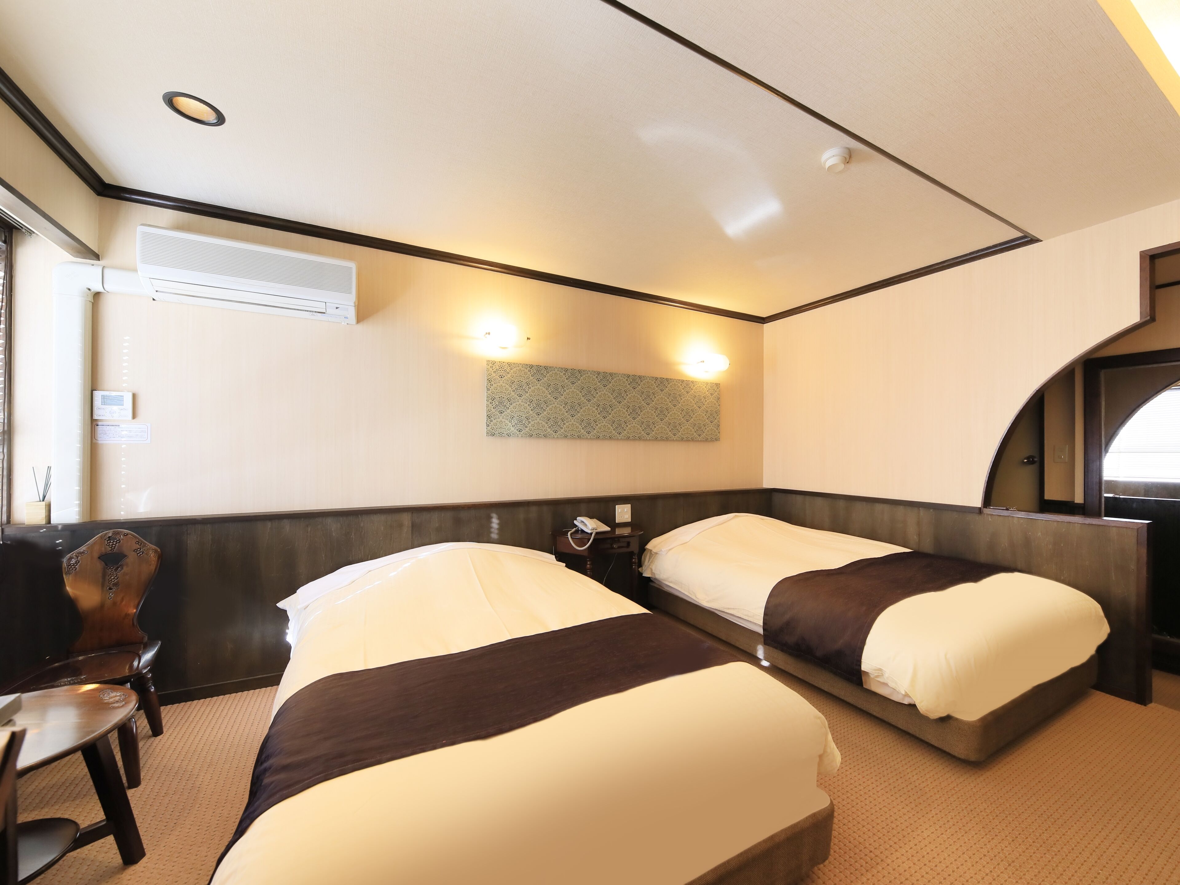 Quarto de hotel com duas camas, uma escrivaninha e uma cadeira.