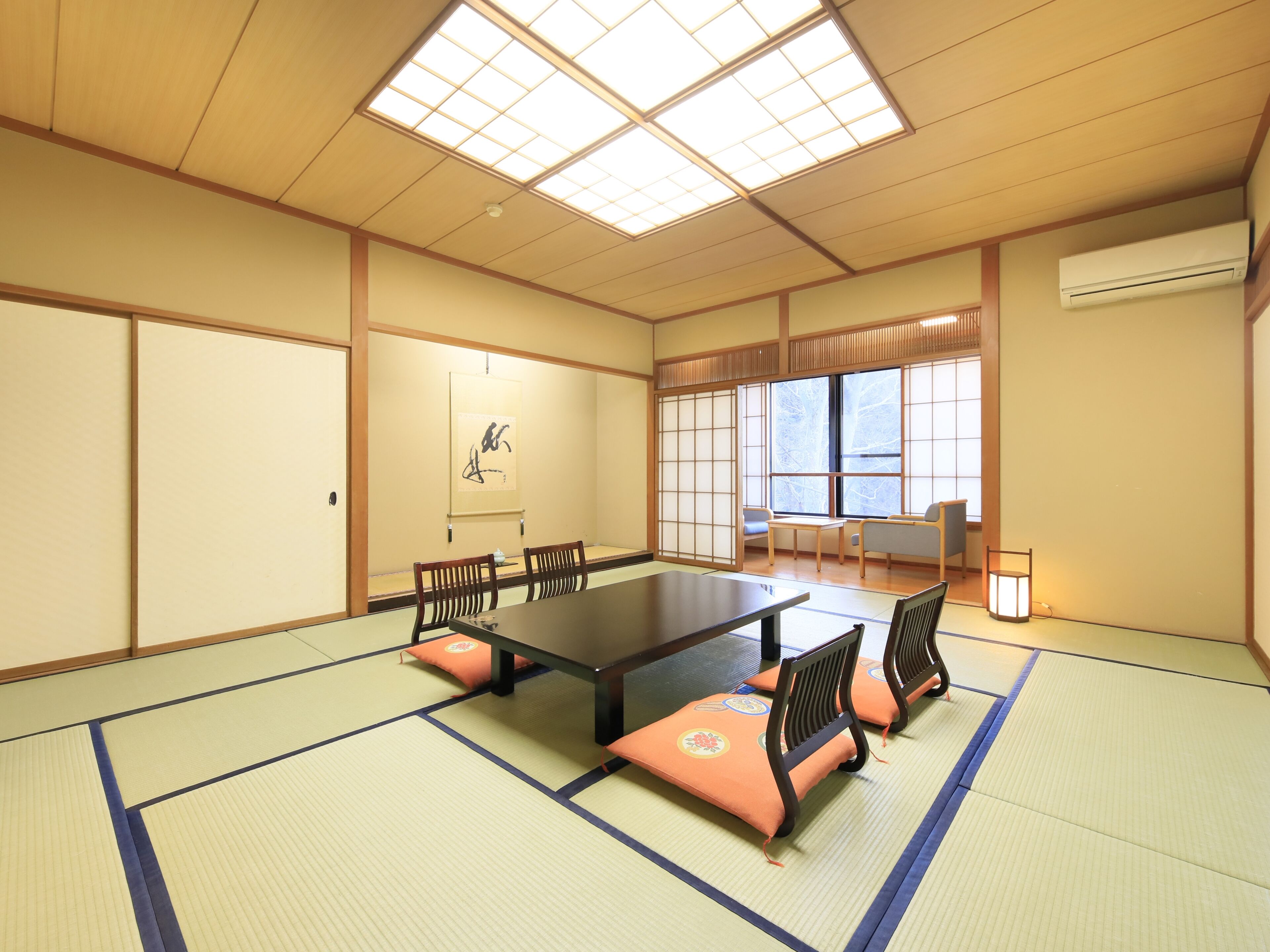Una habitación tradicional con tatamis, una mesa de tatami, sillas de madera, un fusuma y un ventanal con vistas.
