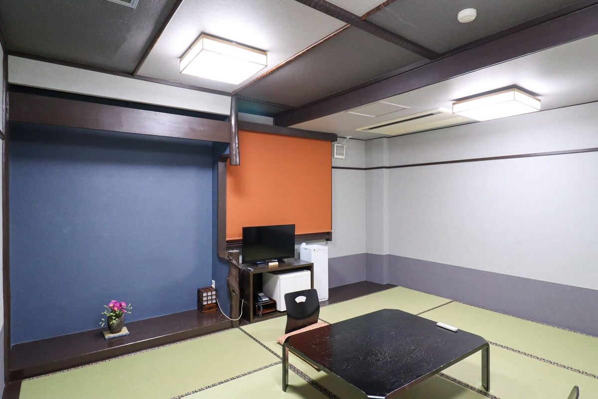 A room with tatami flooring, a television, a small table, and a cabinet.