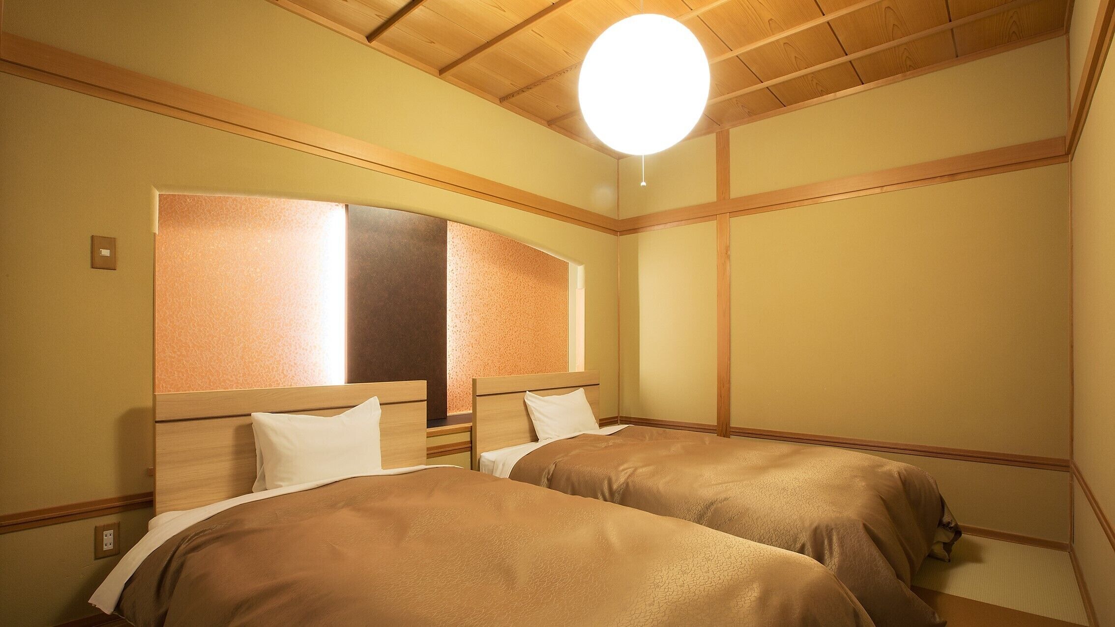 A hotel room with two beds, wooden headboards, a large mirror, and a hanging light fixture.