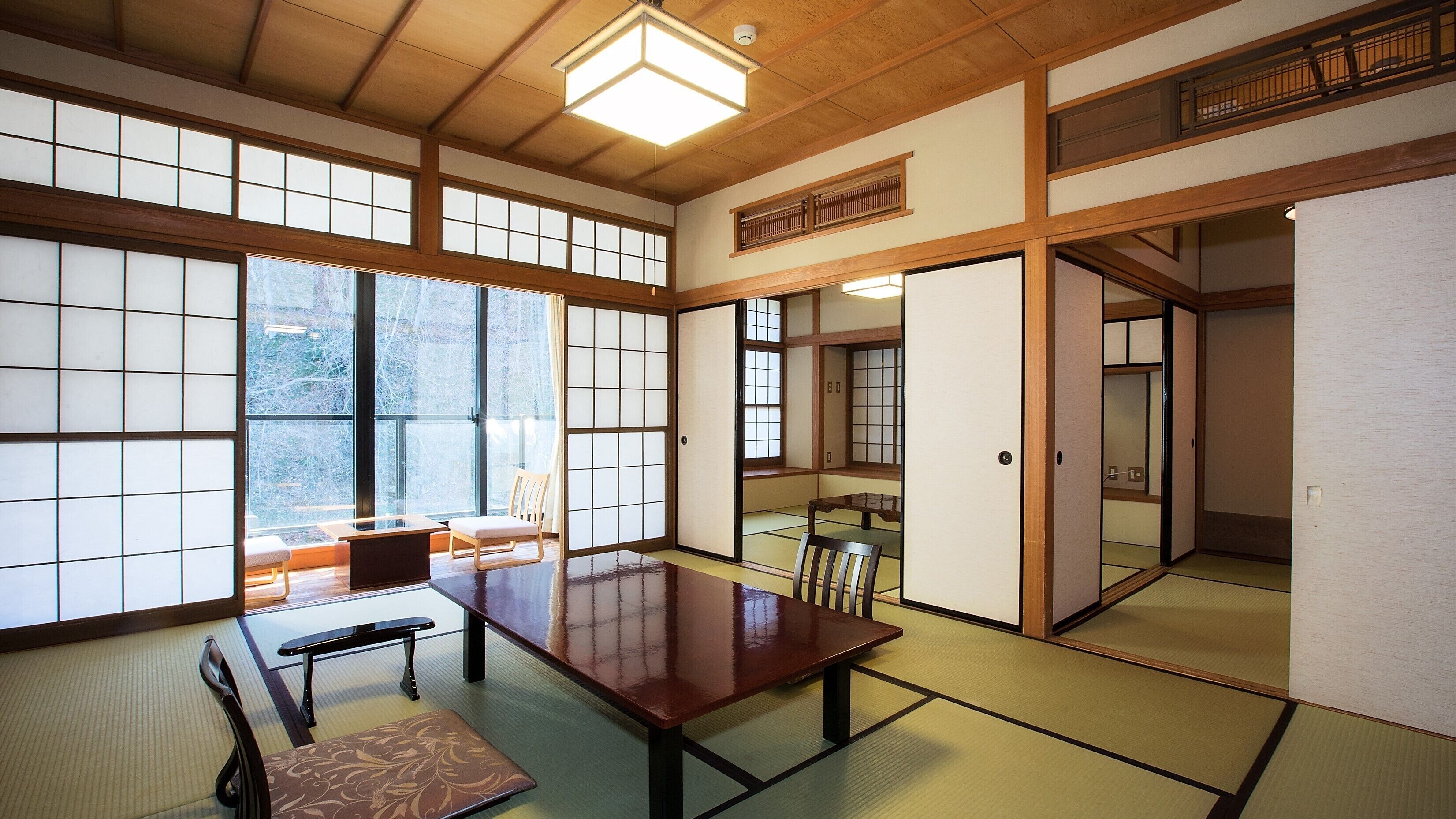 Une pièce de style japonais traditionnel, avec un sol recouvert de tatamis, une table basse et des portes coulissantes.