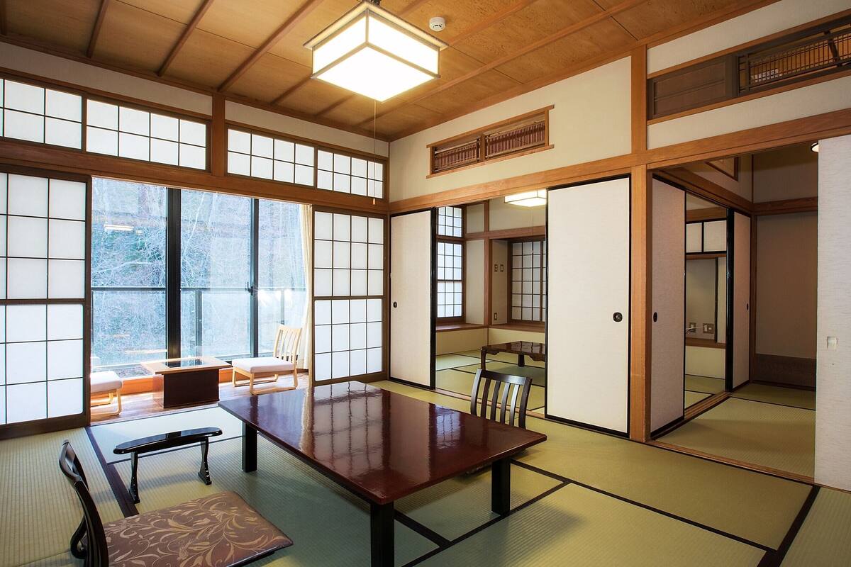 Une pièce de style japonais traditionnel, avec un sol recouvert de tatamis, une table basse et des portes coulissantes.