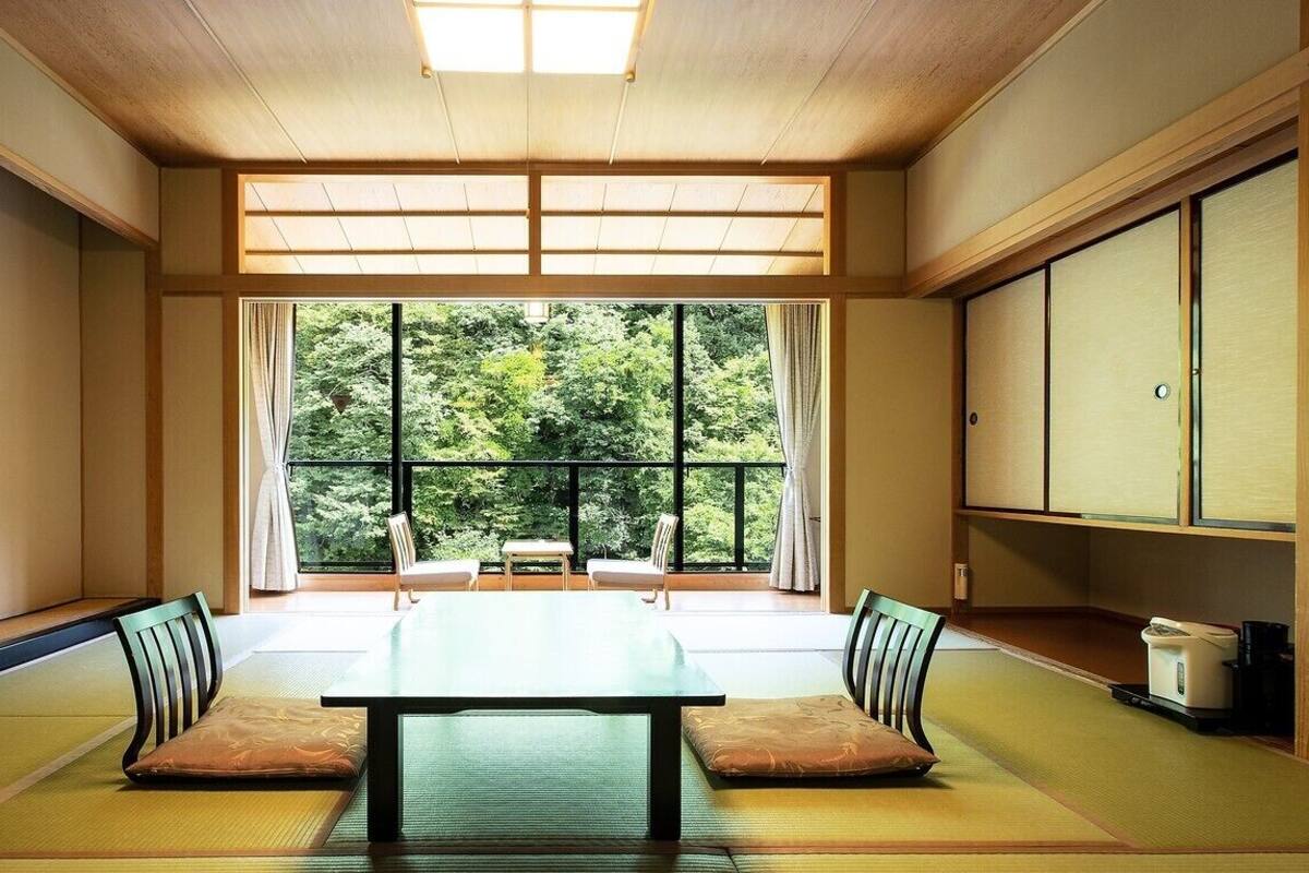 Une pièce de style japonais traditionnel, avec un sol recouvert de tatamis, une table basse et des portes coulissantes.