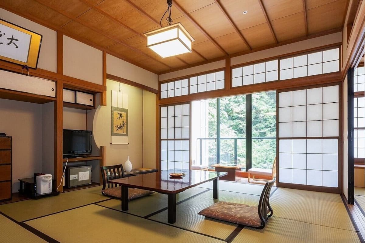 Une pièce de style japonais traditionnel, avec un sol recouvert de tatamis, une table basse, un téléviseur et une porte coulissante.