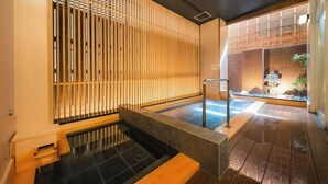 Perinteinen japanilaistyylinen huone, jossa on tatamimatto, liukuva puuovi ja pieni sisätilojen vesiaihe.