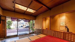 A traditional Japanese room with tatami flooring, sliding doors, and a red carpet leading to the entrance. - Atami Onsen Yamaki Ryokan (Atami)