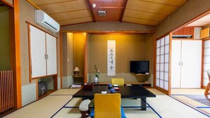 A traditional Japanese-style room with tatami flooring, a low table, and sliding doors. - Atami Onsen Yamaki Ryokan (Atami)