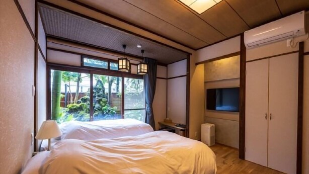 A bedroom with a large bed, a desk, and a wardrobe. - Atami Onsen Yamaki Ryokan (Atami)