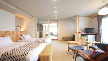 A hotel room with two beds, a desk, a television, and a seating area.