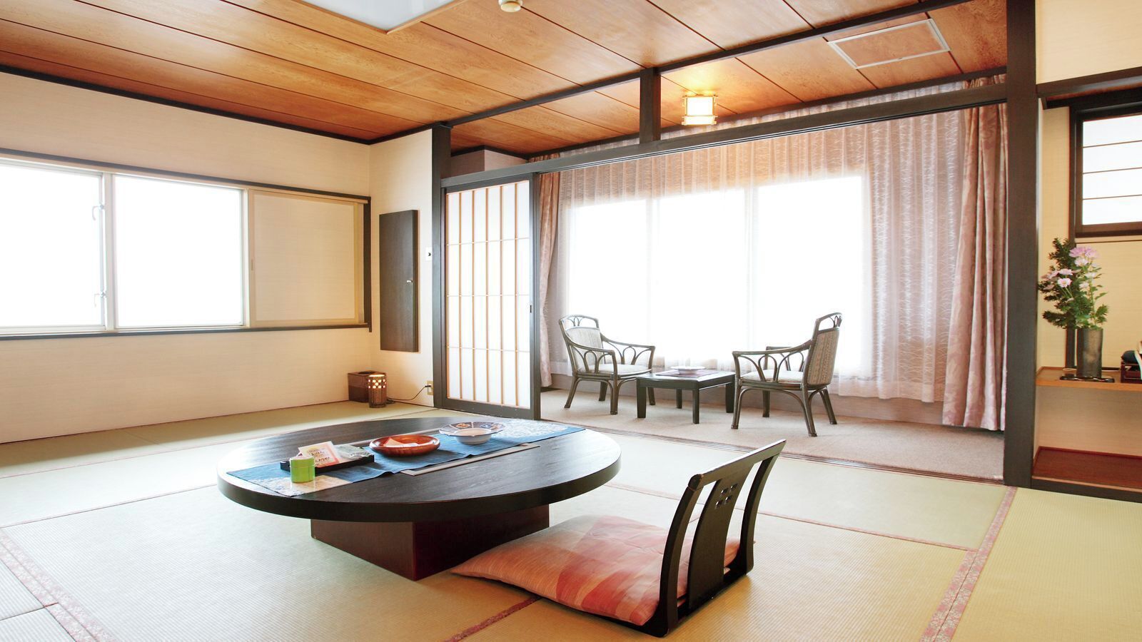 Una habitación con tatamis, una mesa redonda, sillas y una puerta corredera.