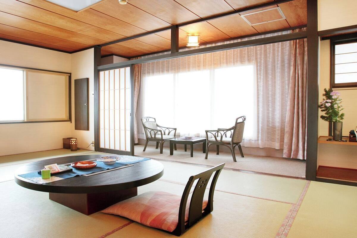 A tatami mat room with a round table, chairs, and a sliding door.